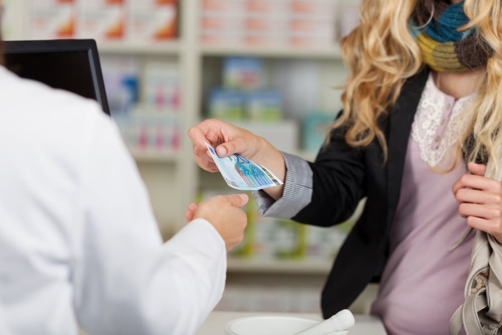 Midsection of pharmacist receiving money from woman for medicines